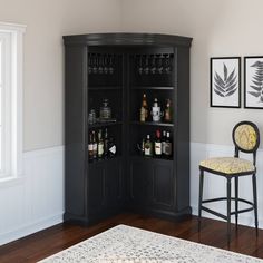 a black cabinet with liquor bottles on it in a living room next to a chair