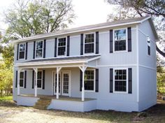 a white two story house with black shutters on the front and second story windows