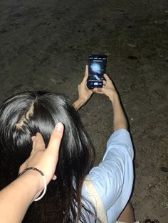 two people holding up their cell phones to take pictures in the dark with one person's hand