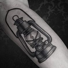 a black and white photo of a lantern tattoo on the right arm, with an hour glass in it