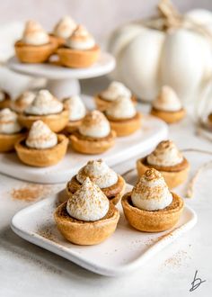 mini pumpkin pies with whipped cream on top are sitting on small white trays