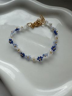 a blue and white beaded bracelet sitting on top of a white platter with a gold plated clasp