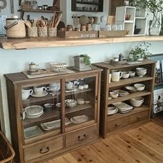 two wooden shelves filled with dishes on top of a hard wood floor next to a wall