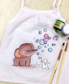 an elephant with bubbles on it's back is next to some paintbrushes