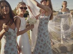 three women in white dresses are standing near each other and one is holding her veil