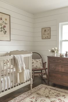 a baby crib in the corner of a room next to a dresser and chair