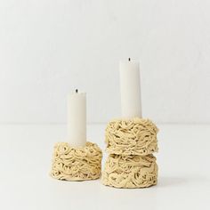 two white candles sitting on top of each other