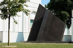 two large black blocks sitting on top of a lush green field next to a building