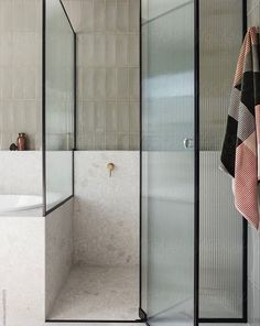 a bathroom with a glass shower door and tiled walls, along with a rug on the floor