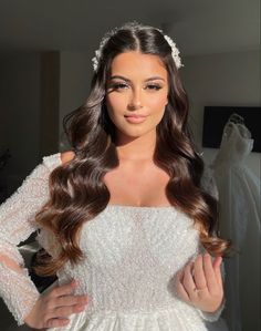 a woman in a wedding dress posing for the camera with her hands on her hips