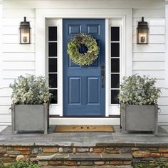 a blue front door with two planters next to it