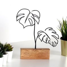 a metal plant sitting on top of a wooden block next to some potted plants