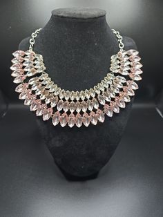 Add a touch of glamour to any occasion with this stunning pink ombré rhinestone bib necklace. The asymmetrical pendant shape and linked style make it a unique and eye-catching piece. The lobster closure and adjustable features ensure a comfortable fit. Perfect for Mother's Day, engagement, graduation, Christmas, wedding, anniversary, Father's Day, birthday, christening, confirmation/communion, or Valentine's Day, this necklace is a versatile addition to any jewelry collection. The necklace length is 16 inches, and it features 83 pink rhinestones with eye-clean clarity grade. The necklace is silvertone with prong setting style and signed by SUGARFIX by BaubleBar. Pink Crystal Rhinestone Necklace In Glamorous Style, Pink Crystal Glamorous Necklace, Elegant Pink Crystal Necklace For Party, Glamorous Pink Crystal Necklace, Pink Rhinestone Jeweled Necklace For Parties, Pink Crystal Rhinestone Necklace With Sparkling Stones, Pink Choker Necklace For Party, Elegant Pink Metal Necklaces, Elegant Pink Rhinestone Necklace With Sparkling Stones