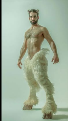 a man with no shirt on standing in front of a white background wearing furry pants