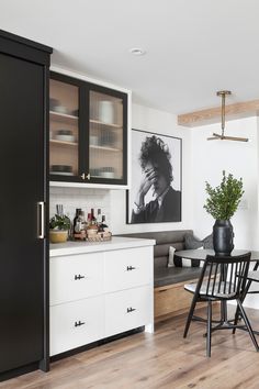 a kitchen with black and white cabinets, wood flooring and a dining room table