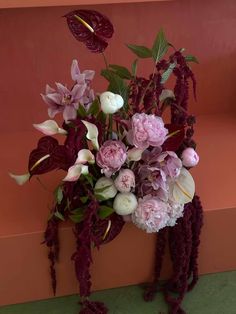 a bouquet of flowers sitting on top of a wooden table next to a pink wall