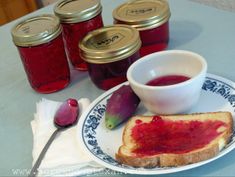 a plate with bread and jam on it next to some pickle halves, spoons and jars