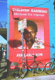 there is a large poster on the side of this building that says, childish gambino because the internet is available now