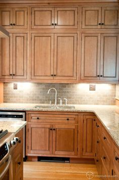 a kitchen with wooden cabinets and marble counter tops