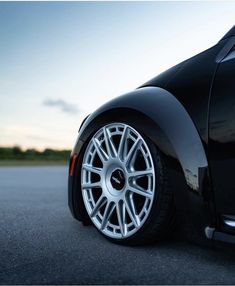 the front end of a black car with chrome spokes