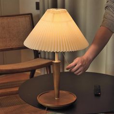 a lamp that is sitting on top of a table next to a chair and remote control