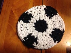 a black and white crocheted hat sitting on top of a wooden floor next to a table