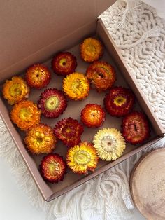 a box filled with lots of flowers on top of a white table next to a doily