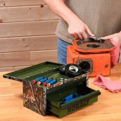 a person standing next to a box with tools in it on a wooden table top