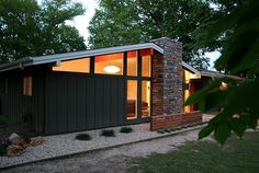 a small house sitting on top of a lush green field next to a forest filled with trees