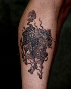 a black and white tattoo on the leg of a man with a dragon in it