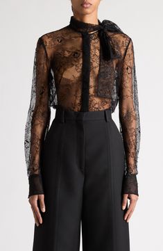 Ornate floral lace conceals and reveals in alluring fashion across this exquisite shirt from Pierpaolo Piccioli's 'Le Noir' collection. This season, the designer takes the typical Valentino frills—ruffles, bows, etc.—and recasts them in timeless, powerful black. 28 1/2" length (size 40IT) Hidden-button placket Mock neck with ties Long sleeves with button cuffs Sheer 56% viscose, 44% polyamide Dry clean Made in Italy Designer Clothing Luxury Long Sleeve Tops With Lace Trim, Luxury Long Sleeve Tops For Wedding, Elegant Formal Tops With Lace Sleeves, Formal Lace Tops With Sheer Sleeves, Elegant Long Sleeve Lace Top For Formal Occasions, Luxury Fitted Tops For Weddings, Luxury Fitted Top For Wedding, Formal Lace Blouse With Sheer Sleeves, Luxury Fitted Tops With Sheer Sleeves