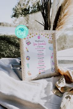 a baby shower sign sitting on top of a white table cloth next to dry grass