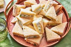 a plate filled with sandwiches next to a cup of green tea