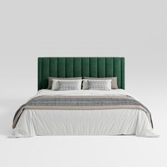 a bed with green velvet headboard and pillows on top of it, in front of a white wall