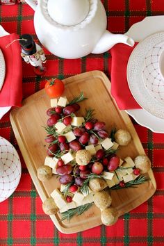 a platter filled with grapes and cheese on top of a red tablecloth covered table