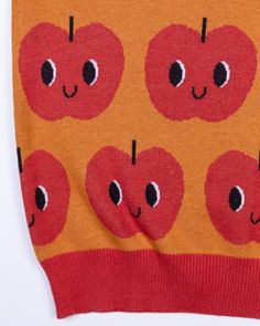 an orange sweater with red apples on it and eyes drawn on the side, all over