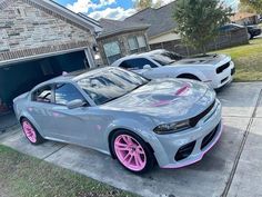 two cars parked next to each other in front of a house with pink rims