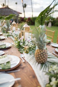 a table set with pineapples, plates and place settings for an outdoor dinner