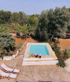 a woman laying on the ground in front of a swimming pool with lounge chairs around it