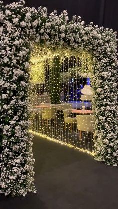 the entrance to an event decorated with white flowers and greenery on display in front of a black backdrop