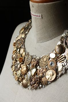 a close up of a necklace on a mannequin with buttons and other items