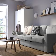 a living room filled with furniture next to a large window and a wooden table on top of a hard wood floor