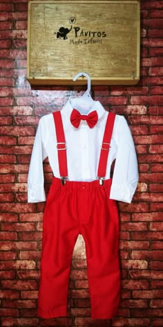 a white shirt and red pants are hanging on a brick wall next to a sign