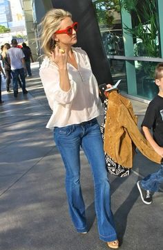 a woman walking down the street talking on her cell phone with a young boy behind her