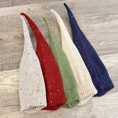 three different colors of knitted mittens sitting on top of a wooden floor