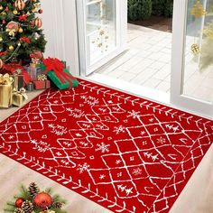 a red rug with white writing on it in front of a christmas tree and presents