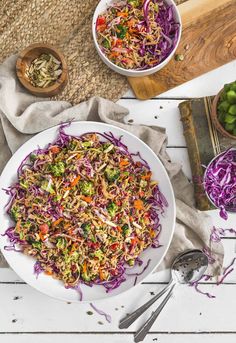 a white bowl filled with coleslaw slaw next to two bowls of salad