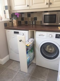 a washer and dryer in a small room with tile flooring on the walls