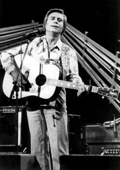 a man holding a guitar while standing next to a microphone