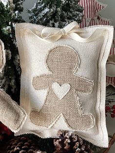 a white pillow with a teddy bear on it next to pine cones and christmas decorations